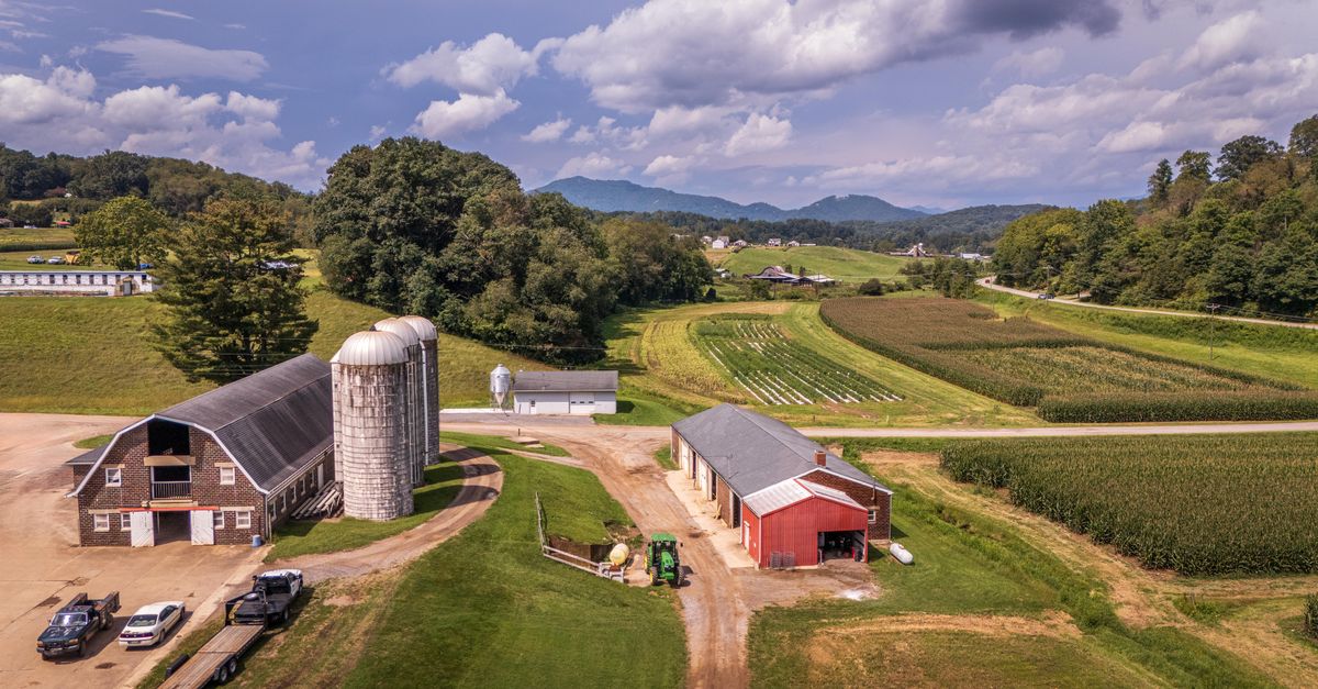 Aerial view of a picturesque farm with silos and barns in the lush North Carolina countryside.